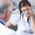 Distraught woman looking down while receiving some upsetting news from her doctor - copyspace